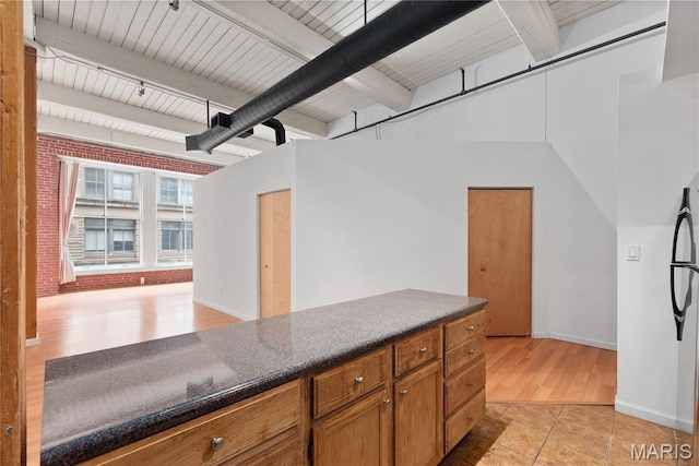 507 N 13th St Unit 207, Saint Louis, MO 63103 - kitchen featuring brown cabinetry, beam ceiling, brick wall, and light tile patterned floors