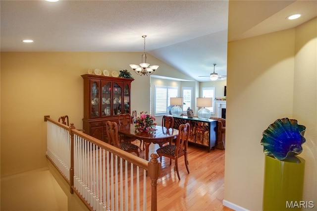 426 Vancroft Pl, Ofallon, IL 62269 - dining area featuring light wood-type flooring, vaulted ceiling, a chandelier, a fireplace, and a ceiling fan
