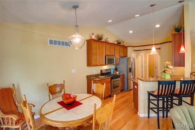 426 Vancroft Pl, Ofallon, IL 62269 - kitchen with stainless steel appliances, lofted ceiling, brown cabinets, light wood finished floors, and a kitchen breakfast bar