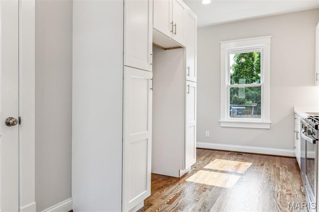 7721 Weaver Ave, Maplewood, MO 63143 - kitchen with light wood finished floors, white cabinetry, light countertops, stainless steel range with gas stovetop, and baseboards