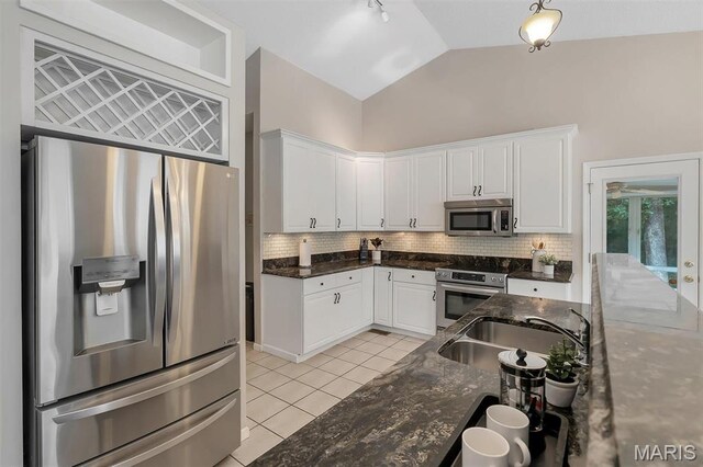 3001 Peach Blossom Ct, High Ridge, MO 63049 - kitchen featuring stainless steel appliances, white cabinetry, light tile patterned floors, vaulted ceiling, and decorative backsplash