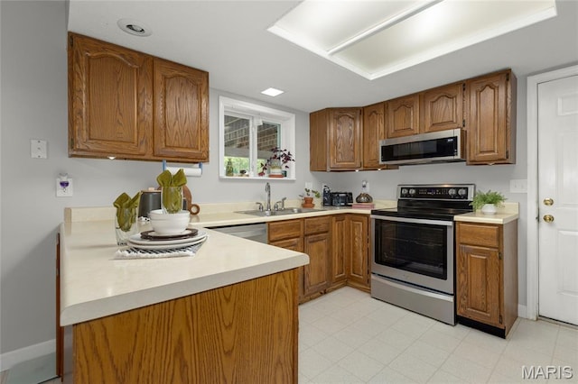 2280 Ebert Ln, Wentzville, MO 63385 - kitchen featuring appliances with stainless steel finishes, brown cabinetry, light countertops, and a peninsula