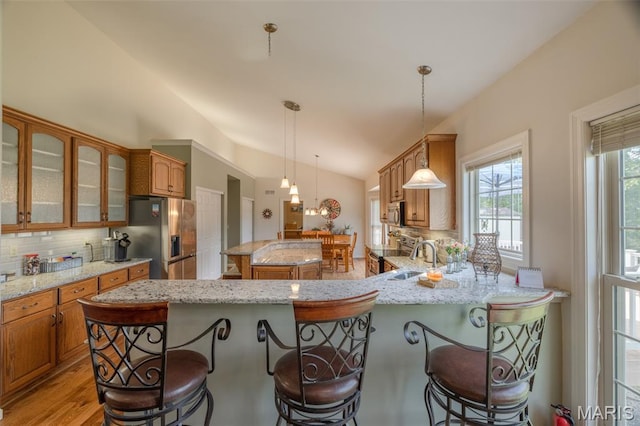 11400 Macs Cove Dr, Wright City, MO 63390 - kitchen featuring appliances with stainless steel finishes, vaulted ceiling, backsplash, a kitchen breakfast bar, and glass insert cabinets