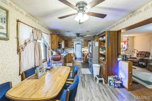 10049 Chateau Rd, Sullivan, MO 63080 - dining space with wallpapered walls, ceiling fan, light wood-style flooring, and a textured ceiling