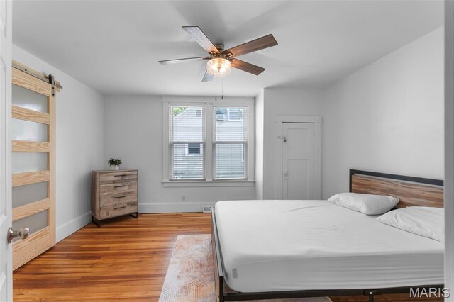 1210 Perryville Rd, Cape Girardeau, MO 63701 - bedroom featuring light wood-style floors, baseboards, a barn door, and a ceiling fan