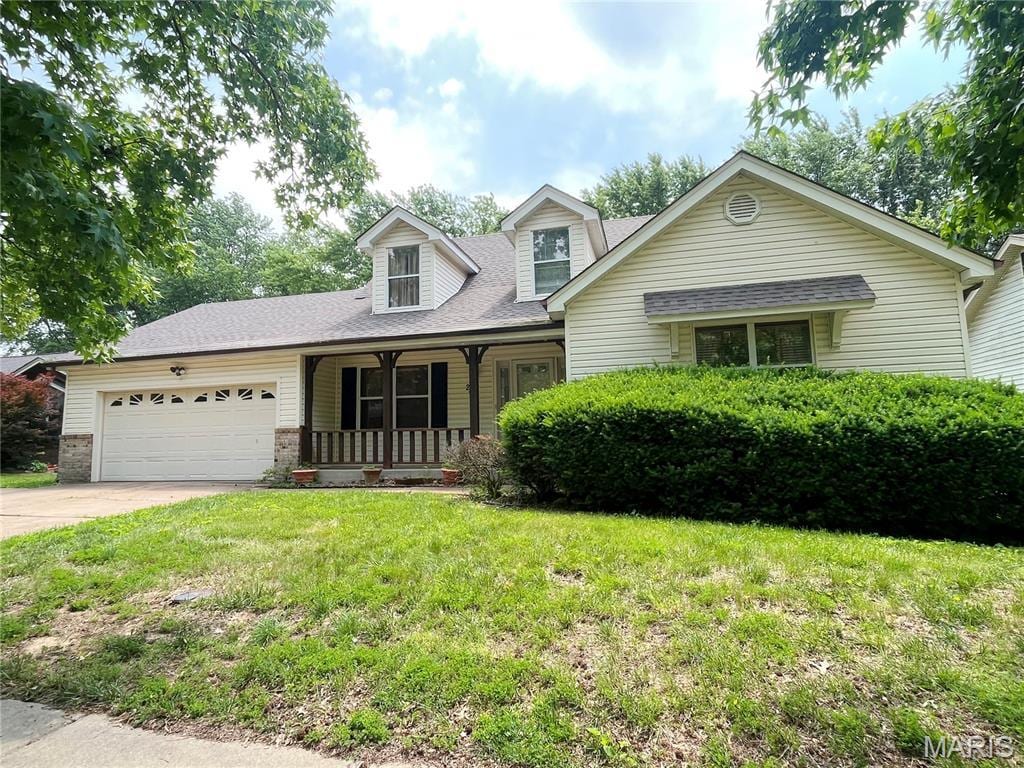 2914 Wood Poppy Dr, Hazelwood, MO 63031 - view of front of home featuring a porch, a garage, a front yard, concrete driveway, and roof with shingles
