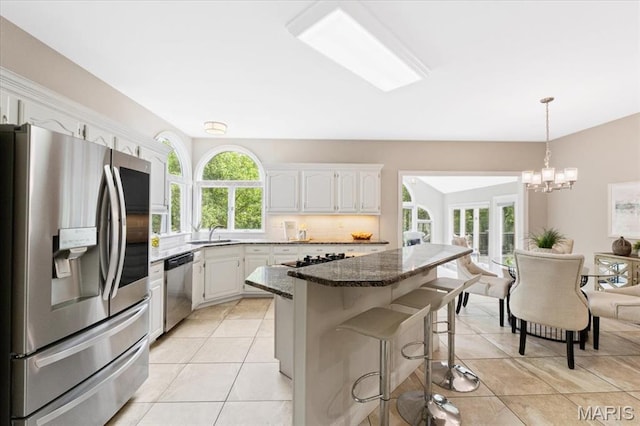 1525 Honey Locust Ct, Wildwood, MO 63005 - kitchen with appliances with stainless steel finishes, a kitchen bar, backsplash, a chandelier, and light tile patterned flooring