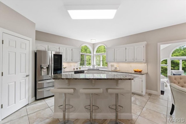 1525 Honey Locust Ct, Wildwood, MO 63005 - kitchen featuring stainless steel refrigerator with ice dispenser, dark stone countertops, white cabinetry, decorative backsplash, and a kitchen island