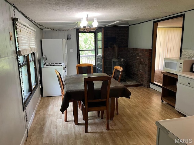 11142 E State Highway 47, Cadet, MO 63630 - dining room featuring a textured ceiling, a wood stove, light wood finished floors, and wood walls