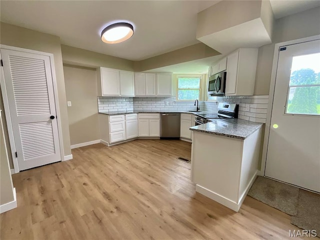 3919 Bellvue Dr, Saint Peters, MO 63376 - kitchen with stainless steel appliances, light wood-style floors, white cabinetry, tasteful backsplash, and a peninsula