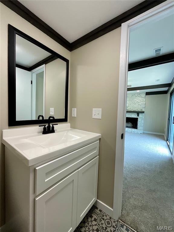 3919 Bellvue Dr, Saint Peters, MO 63376 - bathroom featuring vanity, a stone fireplace, and ornamental molding