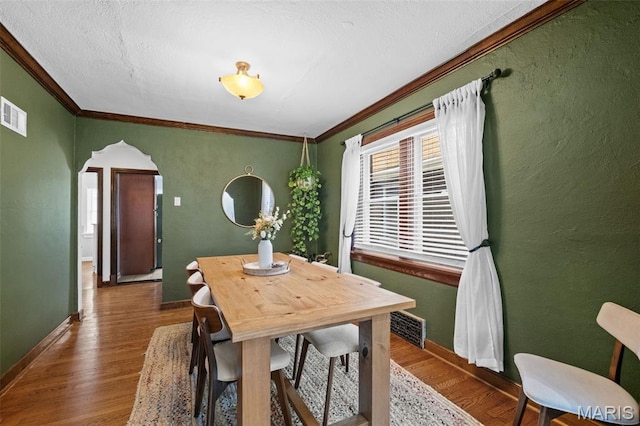 6314 Chippewa St, Saint Louis, MO 63109 - dining space with arched walkways, ornamental molding, wood finished floors, baseboards, and a textured wall