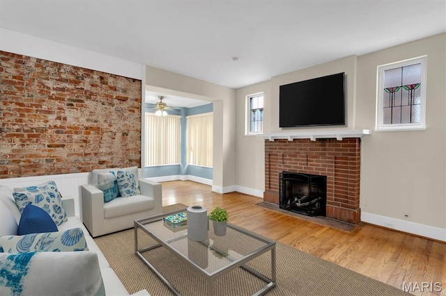 6026 Waterman Ave Unit 3E, Saint Louis, MO 63112 - living area featuring wood finished floors, a brick fireplace, a ceiling fan, and wainscoting