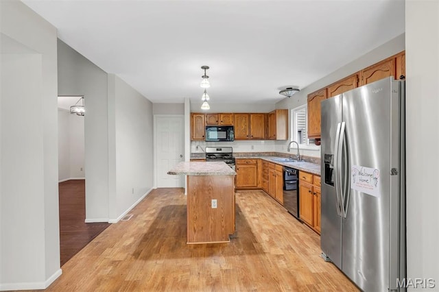 1045 Sprinters Row Dr, Florissant, MO 63034 - kitchen with black appliances, light wood-style floors, light countertops, a sink, and a center island