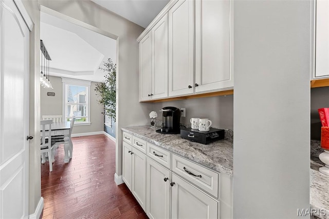 3204 Hadrian St, Saint Charles, MO 63301 - kitchen with dark wood-type flooring, baseboards, white cabinetry, and light stone countertops