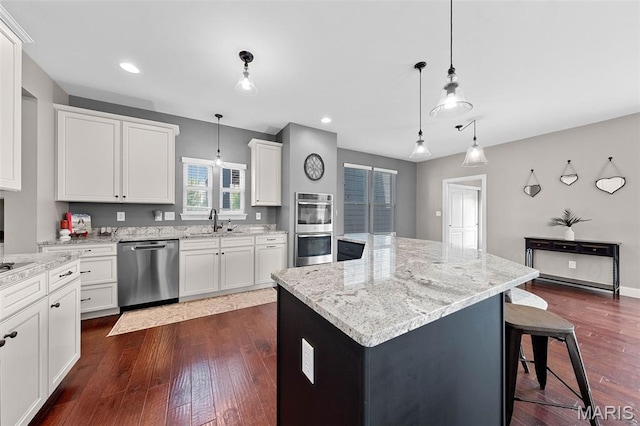 3204 Hadrian St, Saint Charles, MO 63301 - kitchen with appliances with stainless steel finishes, a sink, a kitchen island, dark wood-style floors, and light stone countertops