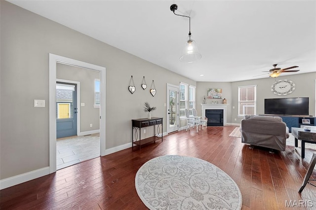 3204 Hadrian St, Saint Charles, MO 63301 - living area with dark wood-style flooring, a glass covered fireplace, baseboards, and a ceiling fan