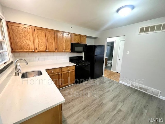 170 Ruth Dr, Florissant, MO 63031 - kitchen with black appliances, a sink, light wood-style floors, and brown cabinetry