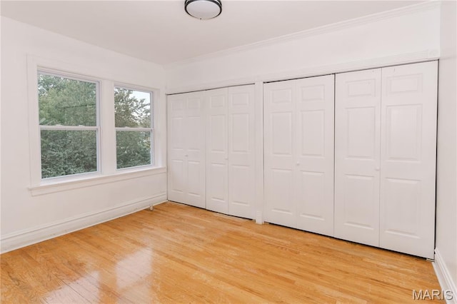 7360 Dartmouth Ave, University City, MO 63130 - unfurnished bedroom with two closets, light wood finished floors, and crown molding