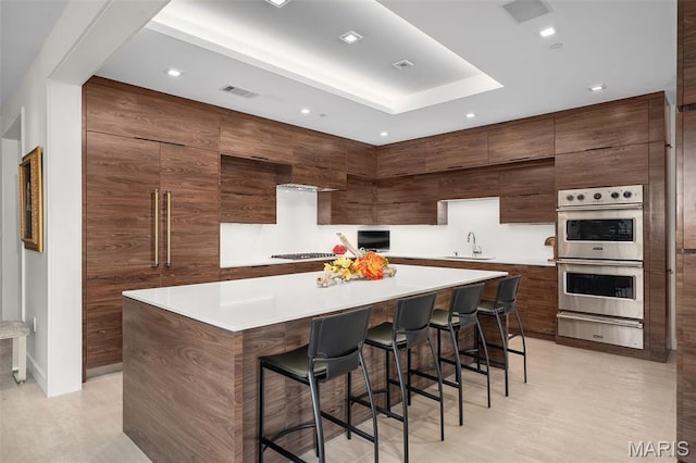 150 Carondelet Plz Unit 702, Clayton, MO 63105 - kitchen with a warming drawer, stainless steel double oven, a kitchen breakfast bar, modern cabinets, and a large island