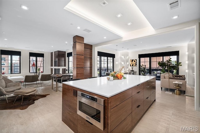 150 Carondelet Plz Unit 702, Clayton, MO 63105 - kitchen with open floor plan, stainless steel microwave, modern cabinets, a large island, and light countertops