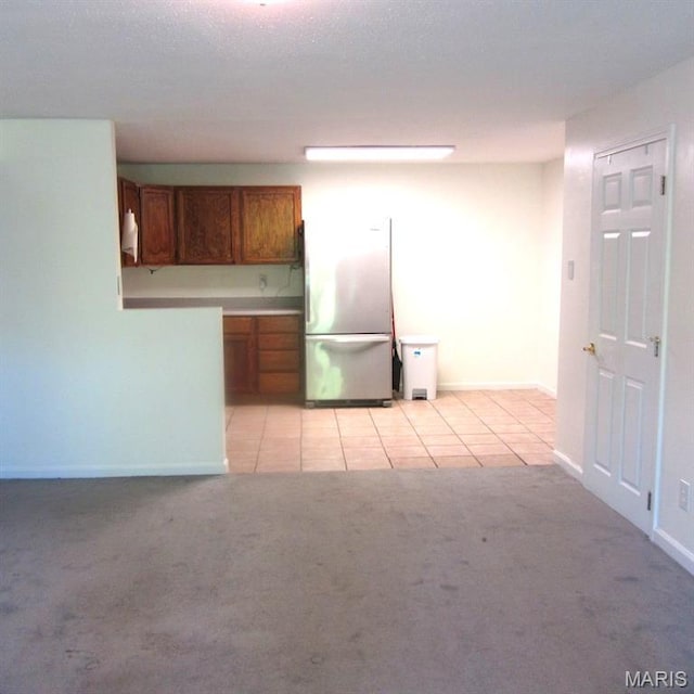 2840 Blackforest Dr Unit B, Saint Louis, MO 63129 - kitchen with freestanding refrigerator, brown cabinets, light carpet, light tile patterned flooring, and baseboards