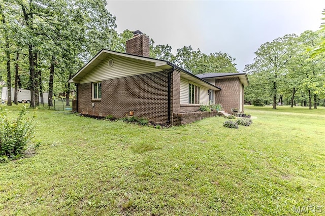 20193 SW Oakwood Dr, Lebanon, MO 65536 - view of home's exterior with brick siding, a chimney, and a yard