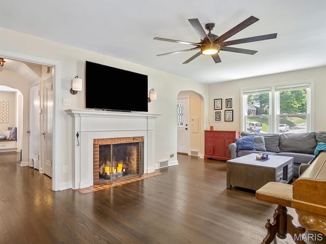 201 Banner St, Edwardsville, IL 62025 - living room featuring arched walkways, a ceiling fan, dark wood-type flooring, a fireplace, and baseboards