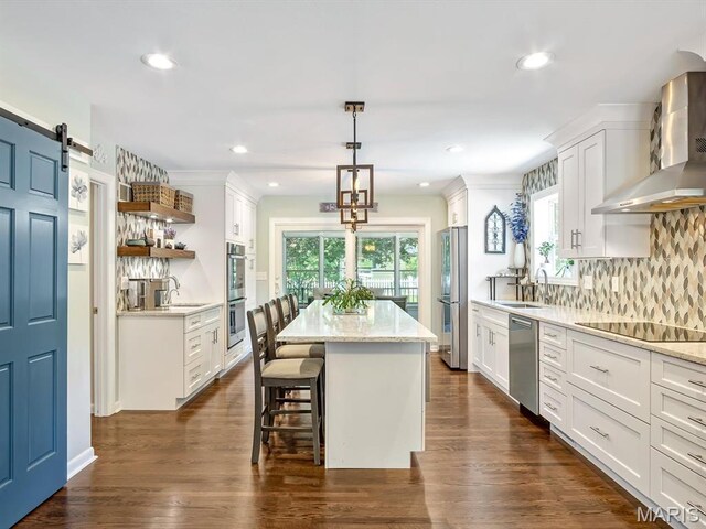 201 Banner St, Edwardsville, IL 62025 - kitchen with wall chimney exhaust hood, appliances with stainless steel finishes, a sink, a center island, and open shelves