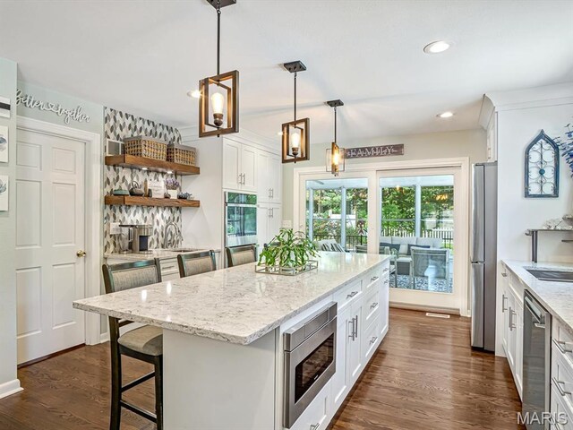 201 Banner St, Edwardsville, IL 62025 - kitchen featuring appliances with stainless steel finishes, white cabinets, a breakfast bar, light stone counters, and recessed lighting