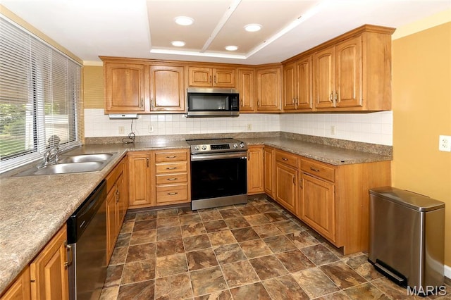 12713 Partridge Run Dr, Florissant, MO 63033 - kitchen with appliances with stainless steel finishes, a sink, backsplash, a tray ceiling, and brown cabinets