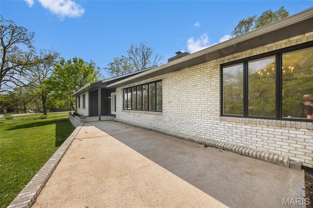 509 Saint Francois Rd, Bonne Terre, MO 63628 - view of side of home featuring brick siding, a patio area, a yard, and a chimney