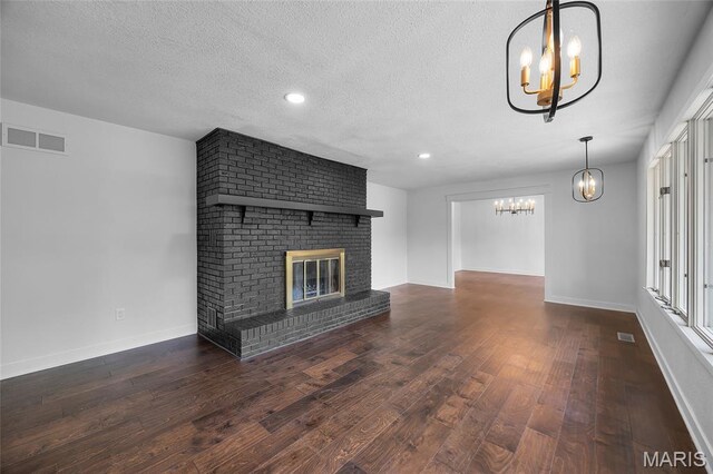 509 Saint Francois Rd, Bonne Terre, MO 63628 - unfurnished living room with a chandelier, wood finished floors, baseboards, a textured ceiling, and a brick fireplace