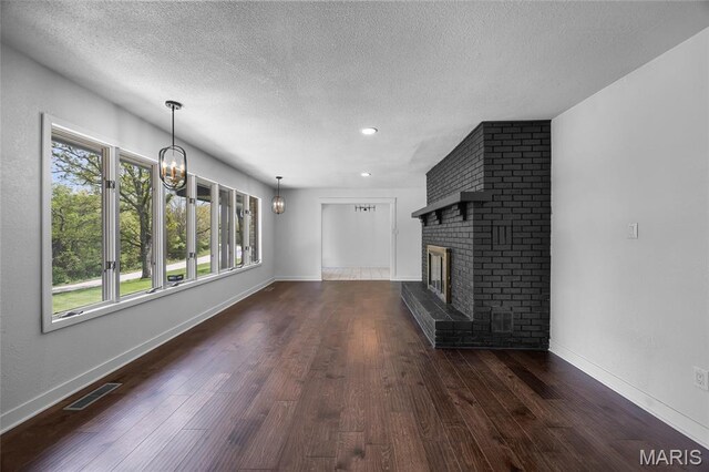 509 Saint Francois Rd, Bonne Terre, MO 63628 - unfurnished living room featuring a textured ceiling, dark wood-style floors, a brick fireplace, a chandelier, and baseboards