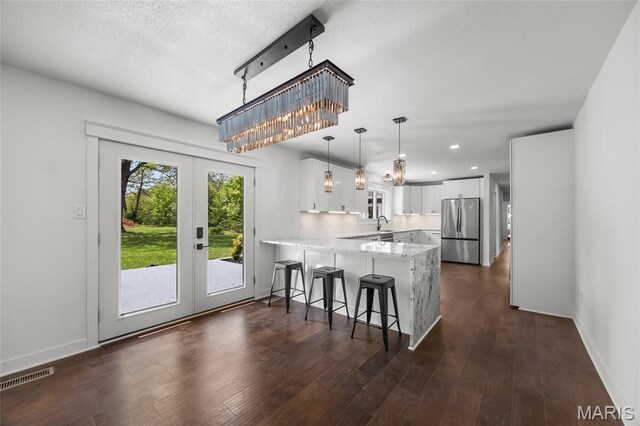 509 Saint Francois Rd, Bonne Terre, MO 63628 - kitchen with freestanding refrigerator, a peninsula, french doors, white cabinetry, and a breakfast bar