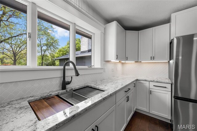 509 Saint Francois Rd, Bonne Terre, MO 63628 - kitchen with freestanding refrigerator, a sink, backsplash, light stone counters, and white cabinets