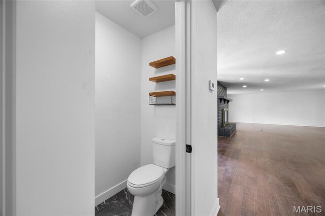 509 Saint Francois Rd, Bonne Terre, MO 63628 - bathroom featuring baseboards, toilet, recessed lighting, wood finished floors, and a brick fireplace