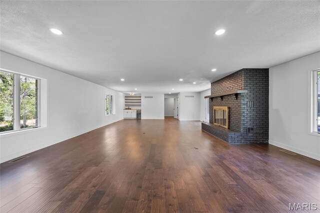 509 Saint Francois Rd, Bonne Terre, MO 63628 - unfurnished living room featuring healthy amount of natural light, a brick fireplace, wood finished floors, recessed lighting, and baseboards