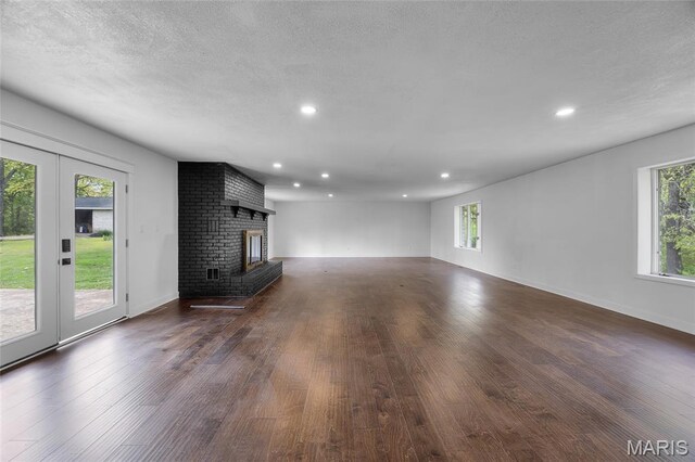 509 Saint Francois Rd, Bonne Terre, MO 63628 - unfurnished living room with dark wood-type flooring, recessed lighting, a brick fireplace, a textured ceiling, and baseboards