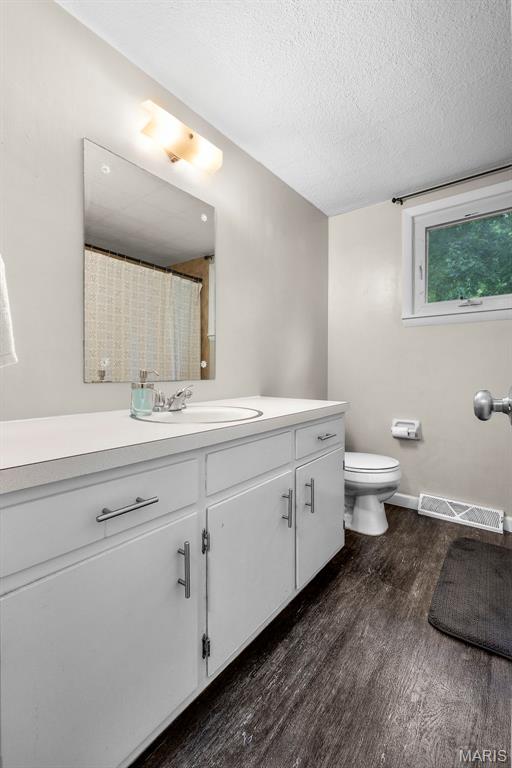 1407 Perry Ave, Cape Girardeau, MO 63701 - full bathroom featuring wood finished floors, vanity, a textured ceiling, toilet, and a shower with shower curtain