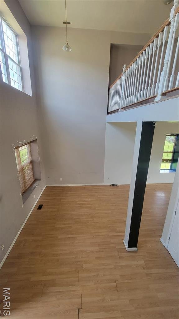 5714 Maple Ave, Saint Louis, MO 63112 - unfurnished living room with a towering ceiling, wood finished floors, and baseboards