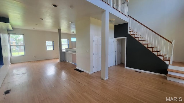 5714 Maple Ave, Saint Louis, MO 63112 - unfurnished living room with light wood-type flooring, plenty of natural light, stairs, and baseboards