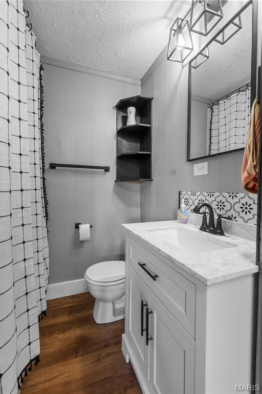 500 Frisco Rd, Campbell, MO 63933 - full bath with a textured ceiling, vanity, toilet, wood finished floors, and curtained shower