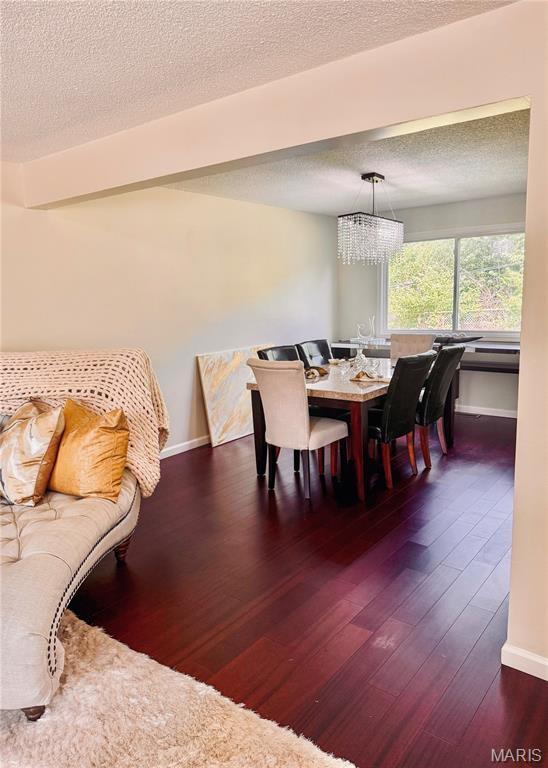 11630 Carolview Dr, Florissant, MO 63033 - dining room with wood-type flooring, a chandelier, a textured ceiling, and baseboards
