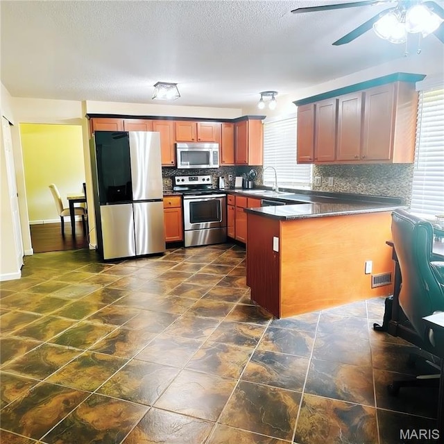 11630 Carolview Dr, Florissant, MO 63033 - kitchen featuring stainless steel appliances, dark countertops, tasteful backsplash, a peninsula, and a ceiling fan