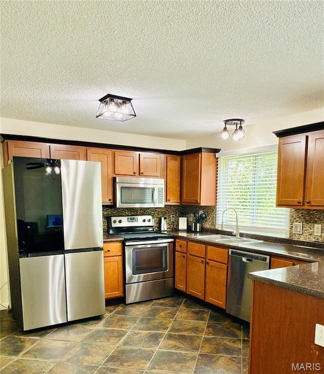 11630 Carolview Dr, Florissant, MO 63033 - kitchen with appliances with stainless steel finishes, a sink, dark countertops, backsplash, and brown cabinetry