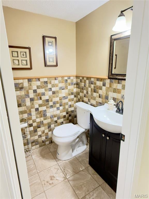 11630 Carolview Dr, Florissant, MO 63033 - half bathroom with toilet, vanity, tile walls, and a wainscoted wall