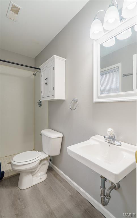 1804 Meadow Ct, Rolla, MO 65401 - bathroom with toilet, wood finished floors, a shower, and baseboards