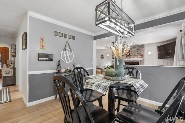 116 Shirewood Dr, Saint Charles, MO 63303 - dining room featuring a fireplace, light wood-style flooring, a chandelier, arched walkways, and crown molding