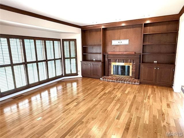 720 Woodridge Heights Ct, Manchester, MO 63011 - unfurnished living room featuring light wood-style flooring, crown molding, a brick fireplace, and built in features
